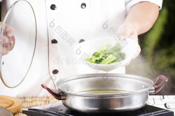 厨师在煮面条之前把蔬菜放在锅里烫伤