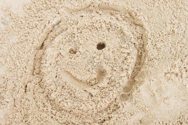 在夏天的海滩沙滩上画着笑脸。 用单调的盐沙画头。