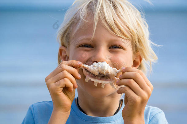 海滩的乐趣，可爱的孩子拿着贝壳捂着嘴