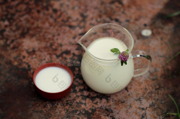 玻璃罐的牛奶与粉红色的三叶草和牛奶滴
