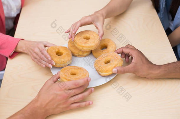 业务团队伸手去拿桌上的甜甜圈