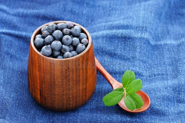 新鲜的野生蓝莓，木制花瓶和木材中有绿叶