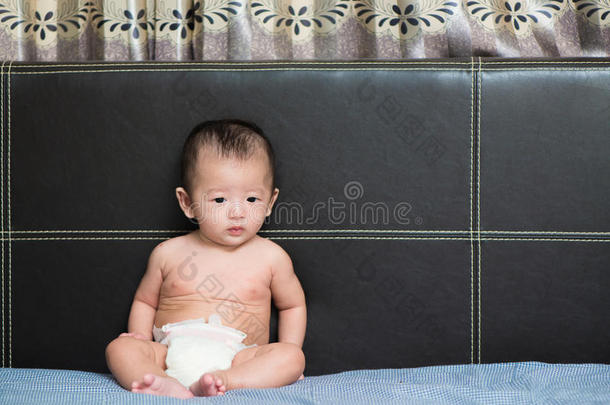 可爱的亚洲宝宝坐在床上，浅浅的Dof，专注于眼睛。