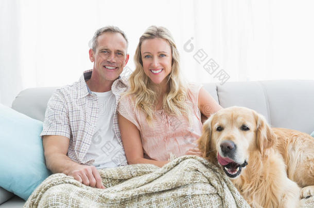 一对<strong>恩爱</strong>的<strong>夫妇</strong>和他们的狗坐在沙发上的毯子下面