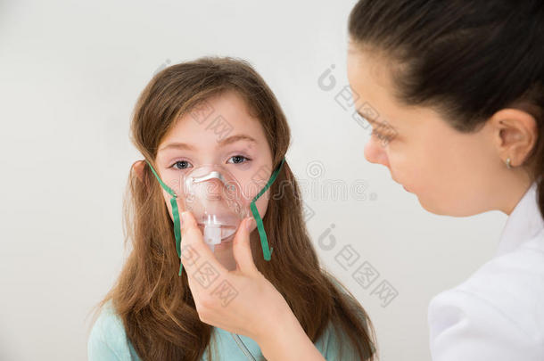 医生拿着吸入器面罩给女孩呼吸