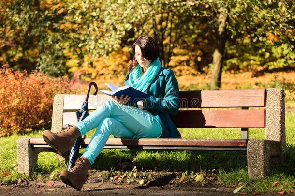 秋天公园里放松的女孩在看书。跌倒。