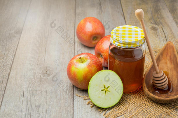 木制背景上的苹果和蜂蜜罐。 犹太罗什哈萨纳（新年）假期