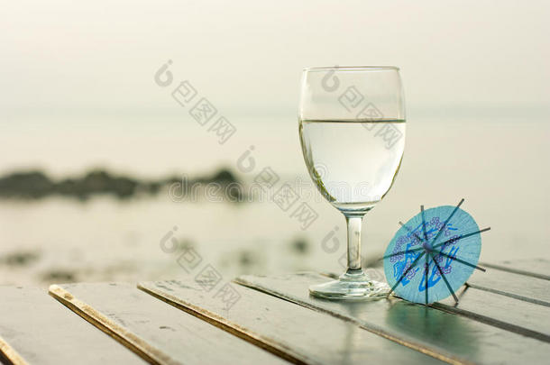 海滩上一张深色桌子上的一杯纯净水