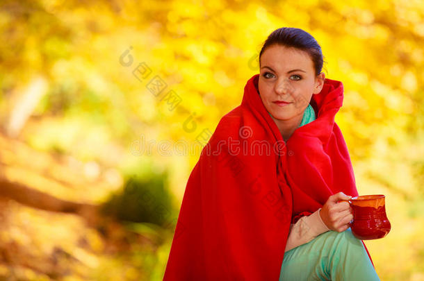 在秋天的公园里放松的女孩在享受热饮