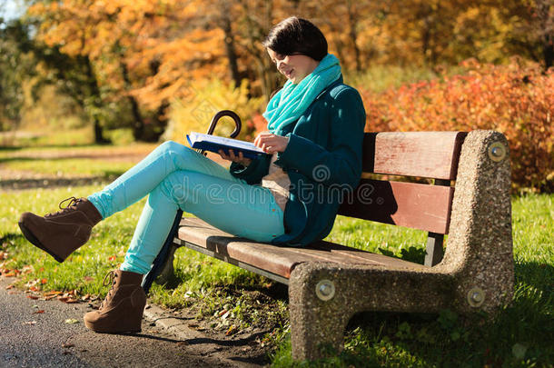 秋天公园里放松的女孩在看书。跌倒。