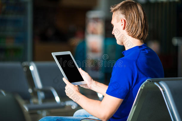 年轻人在机场<strong>候机</strong>时拿着笔记本电脑
