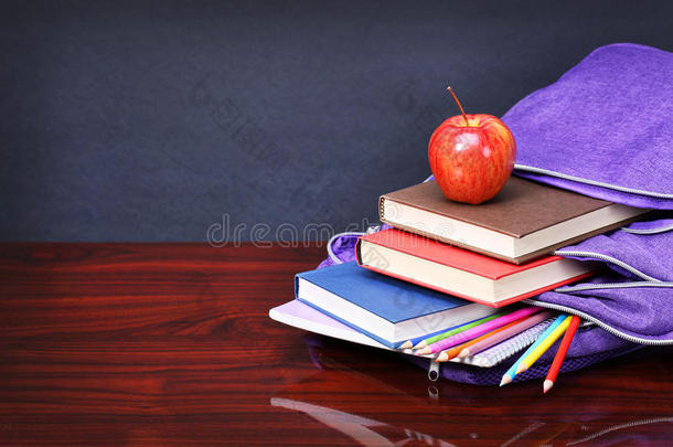 <strong>木头桌子</strong>上的书，苹果，背包和铅笔