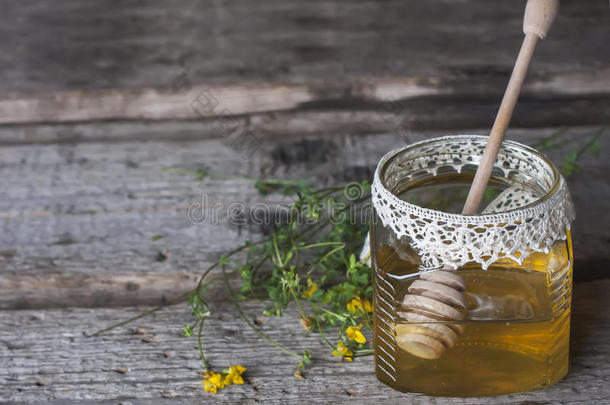 新鲜的天然蜂蜜在一个罐子里，蜂蜜勺子在老式的木制上