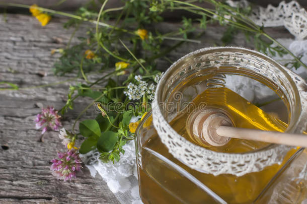 新鲜的<strong>天然蜂蜜</strong>在一个罐子里，<strong>蜂蜜</strong>勺子在老式的木制上