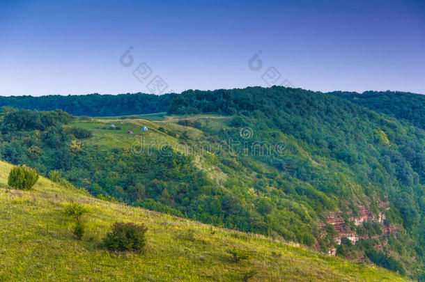 美丽的夏季山景。 森林附近草地上的旅游帐篷。