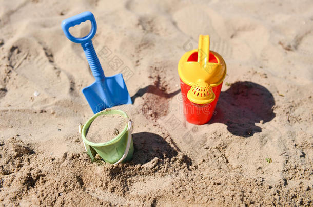 五颜六色的夏季海滩玩具，水桶，洒水器和铲子在沙子上