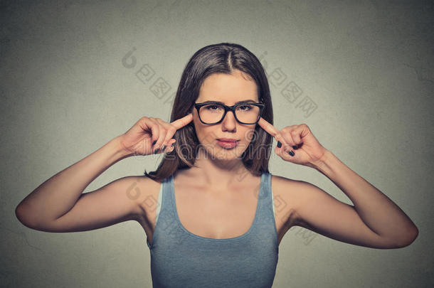愤怒的不快乐的女人戴着眼镜，用手指堵住耳朵