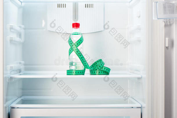 一瓶装有测量胶带的水，放在打开的空冰箱的架子上
