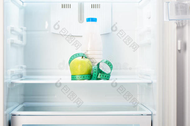 冰箱架子上有测量带和瓶子的苹果