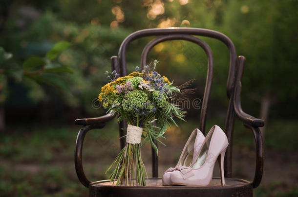 一双漂亮的结婚鞋，高跟鞋和一束五颜六色的花，放在一张古董椅子上，在夕阳下欣赏大自然