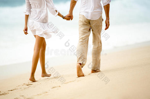 一对夫妇在海滩上牵手散步