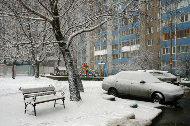 长凳，一辆车和一棵覆盖着雪的树