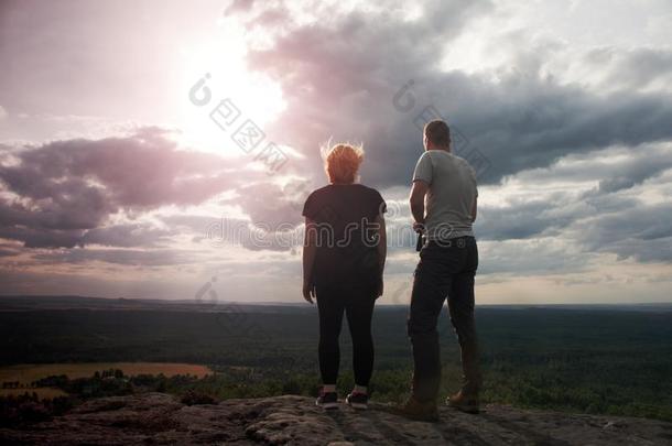一对夫妇在日落时享受着美妙的时刻。 年轻的一对徒步旅行者在岩石帝国公园的山顶上观看山谷。