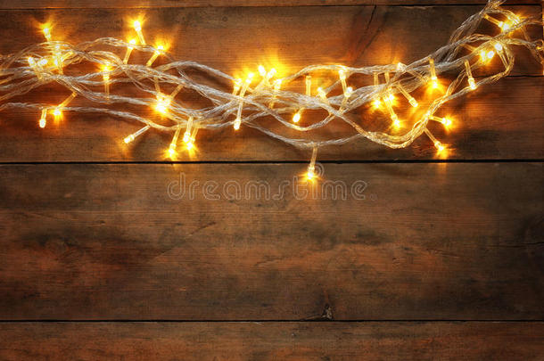 圣诞节温暖的金色花环灯光在木制乡村背景上的抽象照片。 过滤后的图像