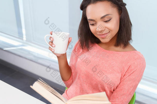 有吸引力的穆拉托女士喝茶和读书