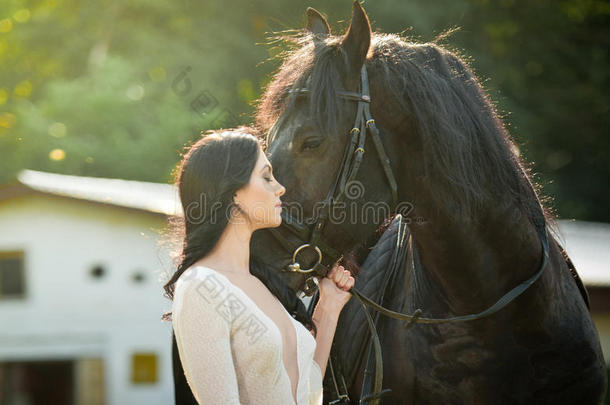 时髦的女士，白色新娘<strong>礼服</strong>，靠近棕色的马。 美丽的年轻女人穿着<strong>长裙</strong>，和一匹友好的马摆姿势