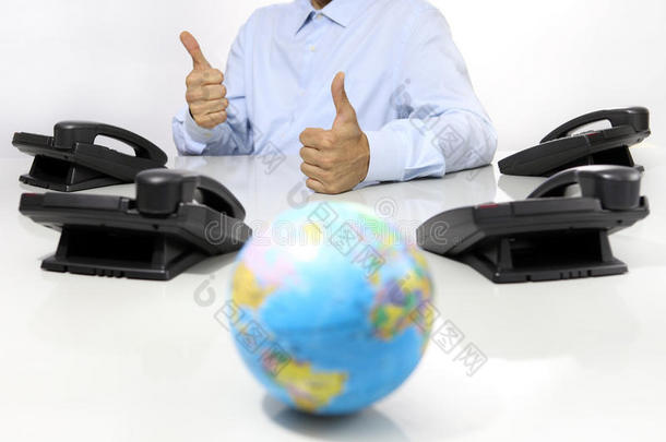 全球和喜欢手与办公电话在办公桌上，全球国际