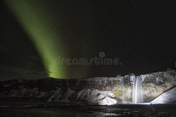 北极光由瀑布在冰岛夜间