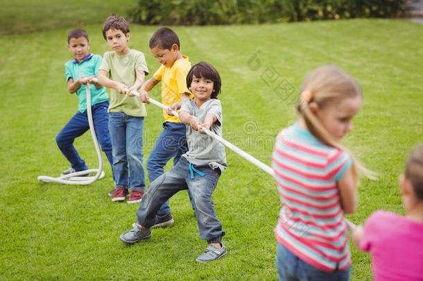 可爱的小学生在外面的草地上玩<strong>拔河比赛</strong>