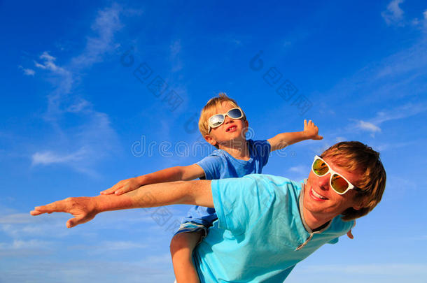 父亲和儿子在蓝色的夏日天空上玩耍