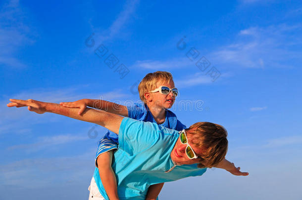 父亲和儿子在蓝色的夏日天空上玩耍