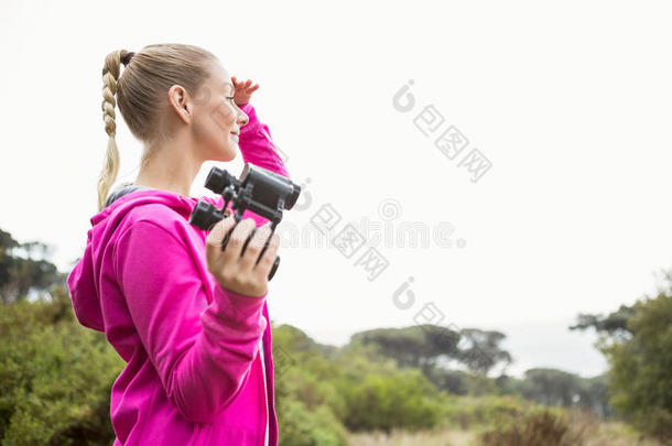 女徒步<strong>旅行</strong>者望着<strong>远方</strong>，拿着望远镜