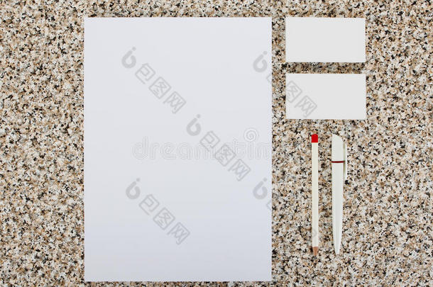 大理石背景上的空白文具。 由名片、A4信头、钢笔和铅笔组成。