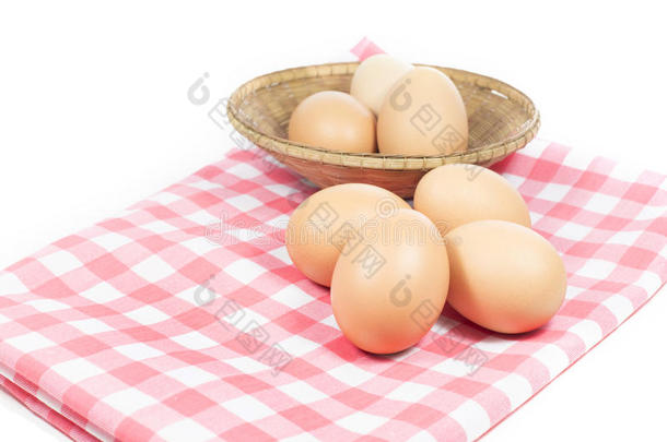 粉红色格子上的鸡蛋和白色背景上的篮子