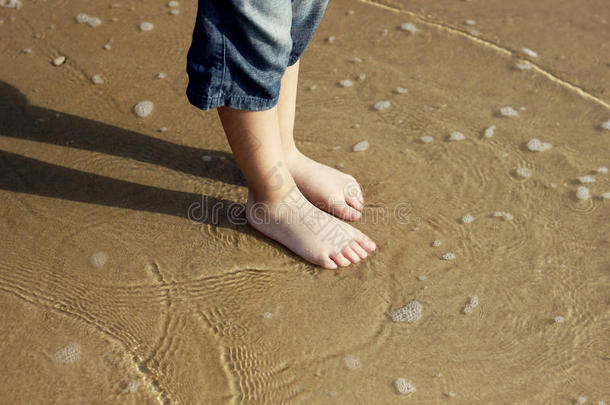 男孩的脚踩在潮湿的沙子上