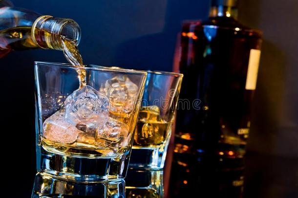 酒保把威士忌倒在两个玻璃杯里，桌上放着冰块，淡蓝色，反光