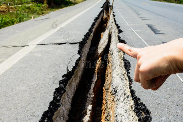 手指向开裂的道路，开裂的道路，地震