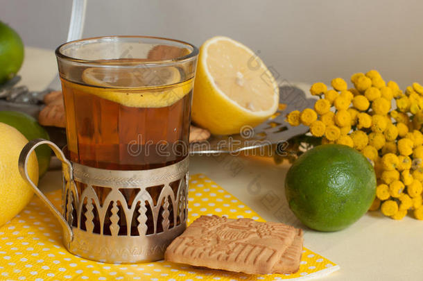 一杯<strong>红茶</strong>在一个玻璃支架，一些饼干，成熟的柠檬和柠檬在亚麻布表面的轻<strong>背景</strong>