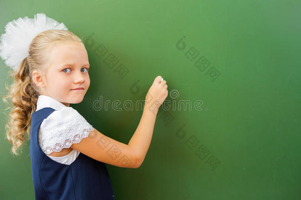 一年级的女学生在教室用粉笔在黑板上写字