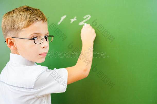 <strong>一年级</strong>的小学生在教室里用粉笔在黑板上写字