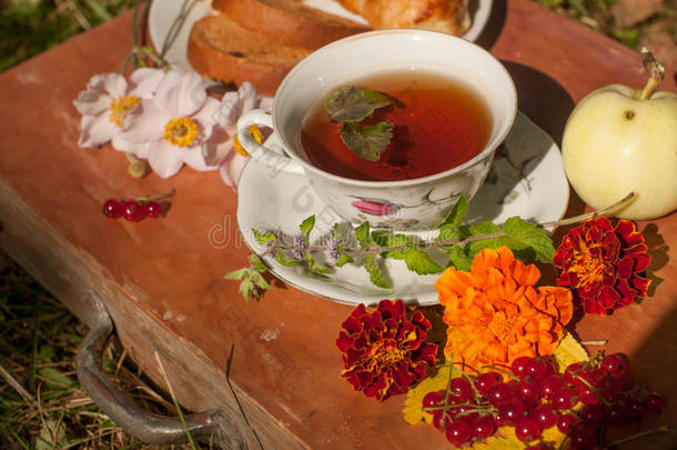一杯凉茶，一盘新鲜的糕点，黄色的秋叶，成熟的<strong>红醋</strong>栗和木制表面的花园花
