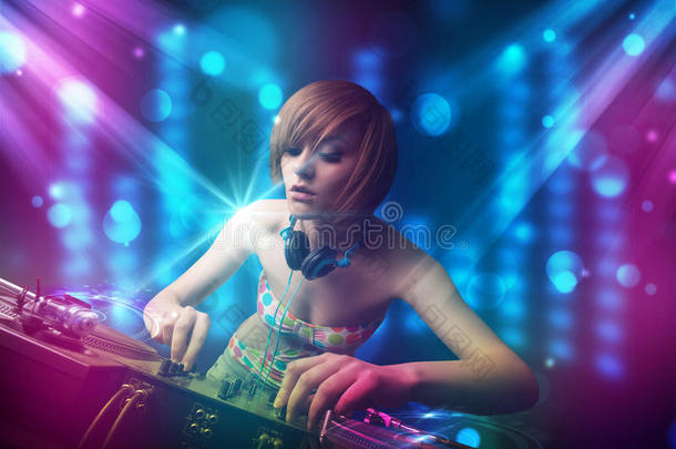 dj女孩在蓝色和紫色灯光的俱乐部里混合音乐