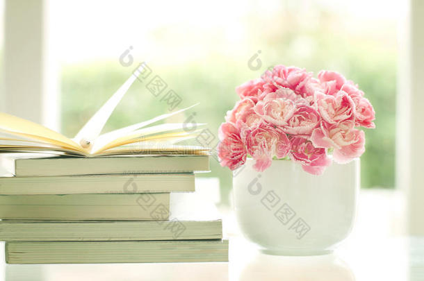 新鲜甜美浪漫的粉红色康乃馨花与书籍背景