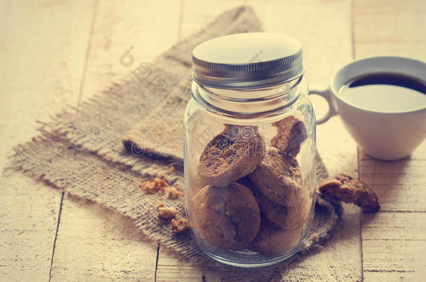 巧克力饼干放在玻璃瓶里，放在麻袋上，咖啡放在木头上