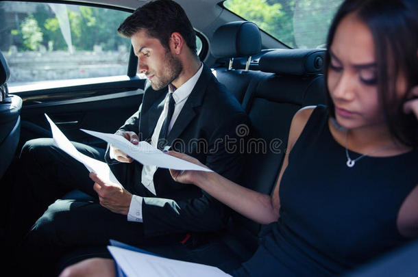 女商人和商人在车里看报纸