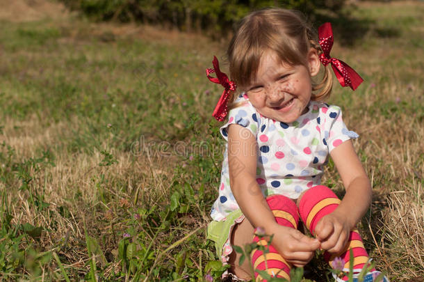 一个小女孩坐在草地上，展示皮皮长袜子和做脸